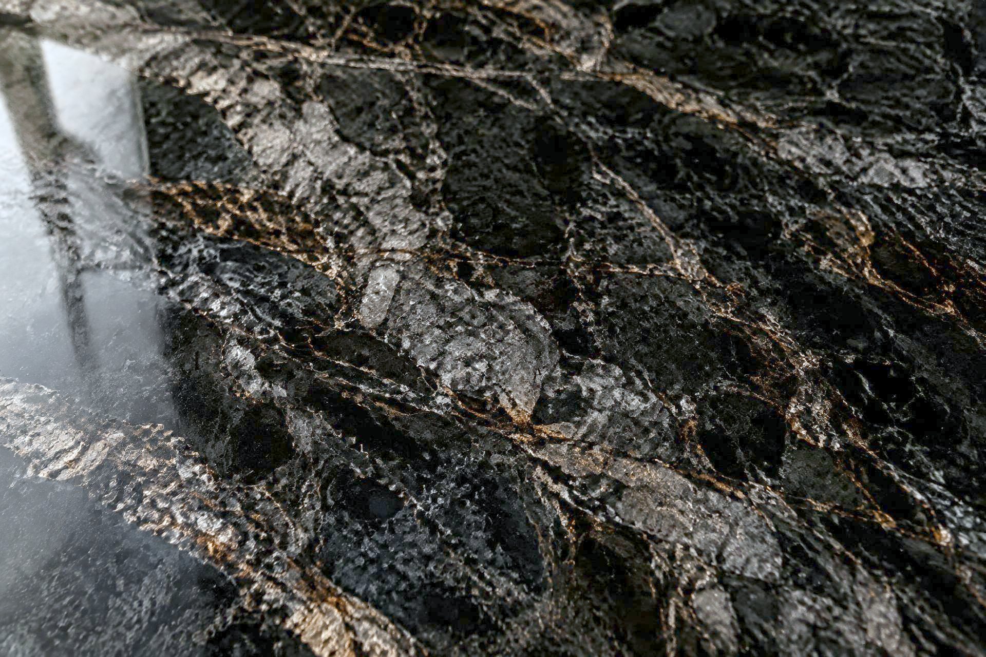 Polished black granite slab with bronze veining